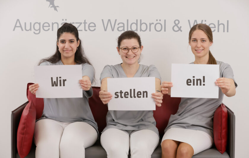 Drei Mitarbeiterinnen halten Schilder in die Höhe - 
